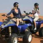 tourists enjoying quad biking in the deep desert of ras al khaimah, with sand surfing on quad bike tour ras al khaimah